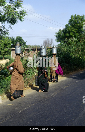 Drei Frauen tragen Milchkannen auf dem Kopf in der Nähe von Vadodara oder Baroda im ländlichen Gujarat, Nord-Indien Stockfoto