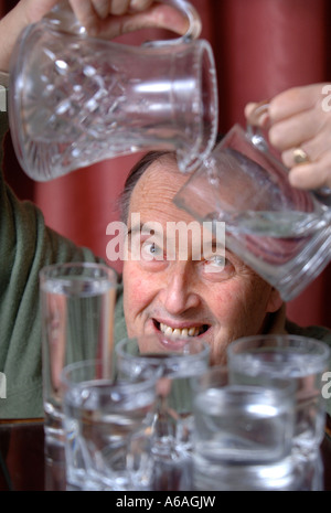 EIN PENSIONIERTER MANN, GIEßEN EIN GLAS WASSER UK Stockfoto