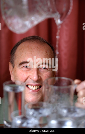 EIN PENSIONIERTER MANN, GIEßEN EIN GLAS WASSER UK Stockfoto