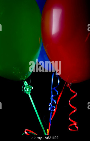 Bunte Luftballons auf Bändern auf schwarzem Hintergrund Stockfoto