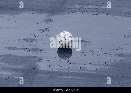 Abgenutzte Fußball liegen in Regen Pfütze (Schwarzweiß) Stockfoto