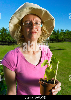 Dame im Garten eine Topfpflanze in einer Hand bereit für auspflanzen hält stand Stockfoto