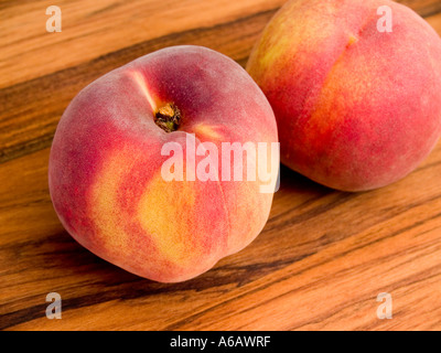 Zwei frisch gepflückter Pfirsiche Prunus Persica sitzen auf einem hölzernen Brot-Brett Stockfoto