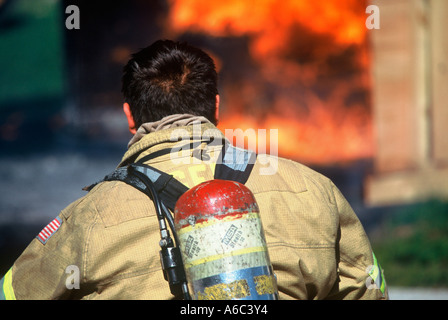 Ein Feuerwehrmann ist Ausrüstung anziehen und immer bereit, löschte ein Feuer vor ihm Stockfoto