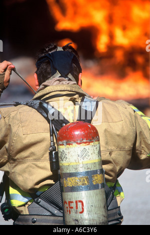 Ein Feuerwehrmann ist Ausrüstung anziehen und immer bereit, löschte ein Feuer vor ihm Stockfoto