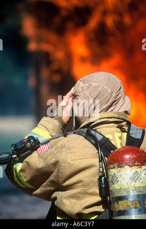 Ein Feuerwehrmann ist Ausrüstung anziehen und immer bereit, löschte ein Feuer vor ihm auf einen Notruf zu tätigen. Stockfoto