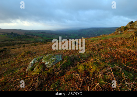 Winterlichen Sonnenaufgang von Bell Tor mit Bonehill Felsen in der Mitteldistanz und Widecombe in weiter Ferne mit stürmischen Himmel Stockfoto