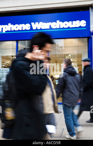 Mann auf dem Handy geht vorbei an Carphone Warehouse Shop auf der Oxford Street Stockfoto