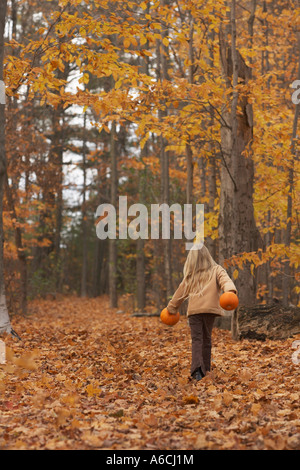 Mädchen zu Fuß durch Herbstlaub Stockfoto