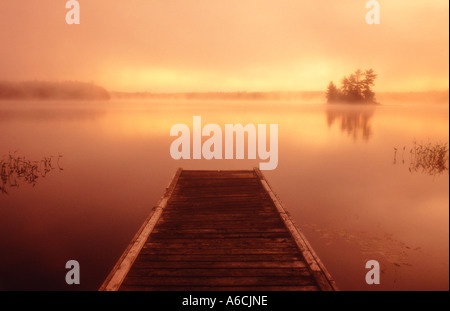 Kanada Ontario Mackay See Sonnenaufgang in der Morgendämmerung mit Holzsteg und Insel in Ferne Stockfoto