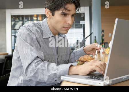 Mann mit Laptop und Essen Stockfoto