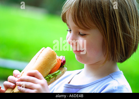 KLEINES MÄDCHEN BLICK AUF SALAT BAGUETTE IM GARTEN UK Stockfoto