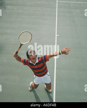 sportlicher junger Mann Portion Ball im Tennis-match Stockfoto