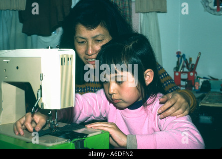 8299 chinesische Mutter lehrt sieben Jahre alte Tochter die Verwendung der Nähmaschine Stockfoto