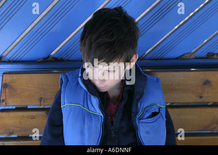 Ein achtjähriger Junge ruht auf einer Parkbank, Highgate Woods, London, UK. Stockfoto