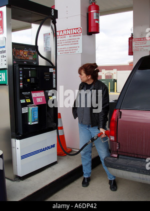 Frau Füllgas fressenden Chevy Suburban an Tankstelle Stockfoto