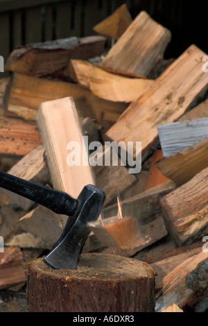 Splitting Maul teilt Protokoll sich in zwei Stücke auf Hackklotz mit Haufen von Spaltebrennholz Stockfoto