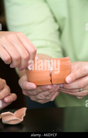 Hände, die zerbrochene Tonscherben Zusammenstellung Stockfoto