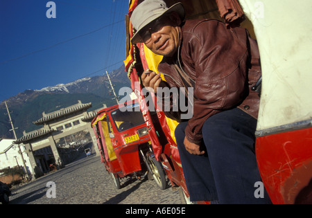 Chinesische Dreirad-Fahrer in Dali Jade Green Mountains im Hintergrund, Yunnan Stockfoto