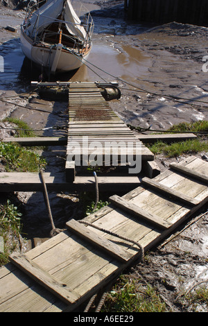 Bande Planken führen über Schlamm zu einer Yacht auf dem Fluß Parrett Somerset England UK Stockfoto