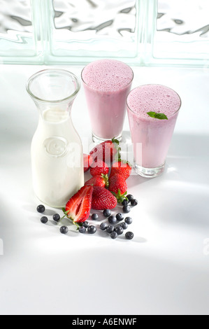 Milch-Botte mit zwei Gläser Erdbeer Milchshake, umgeben von Obst Stockfoto