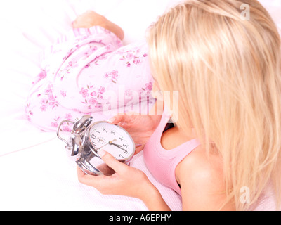 Junge Frau im Bett Einstellung Wecker Modell veröffentlicht Stockfoto