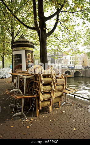 Korbsessel eines Restaurants gestapelt vor eine Gracht in Amsterdamm Stockfoto