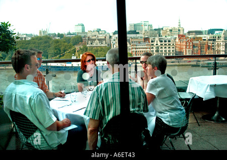 LONDON Großbritannien, Großbritannien, Gruppenmenschen, Junge Erwachsene, die sich am Tisch auf der Terrasse des 'oxo Restaurant' mit Blick auf die Skyline unterhalten, Raucherrestaurant Stockfoto