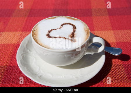 Cappuccino Kaffee mit Herz auf rot aufgegebenes Tischdecke Stockfoto