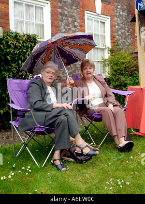 Zwei Frauen Zuflucht vor dem Regen unter einem Regenschirm während eines Gewitters Stockfoto