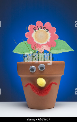 Ton-Blumentopf mit grünen Rasen wächst in einem blauen Hintergrund Stockfoto