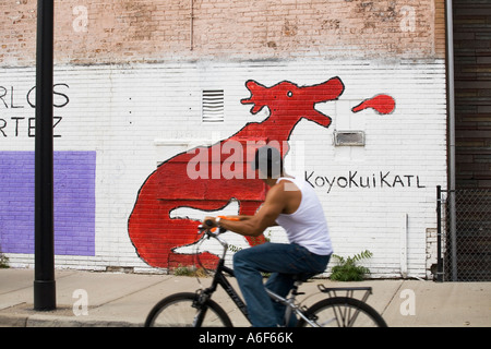 ILLINOIS-Chicago-Mann Fahrt Fahrrad vorbei an outdoor Wandbild Pilsen Viertel am in der Nähe von Südseite Schweinekotelett in der Luft Stockfoto