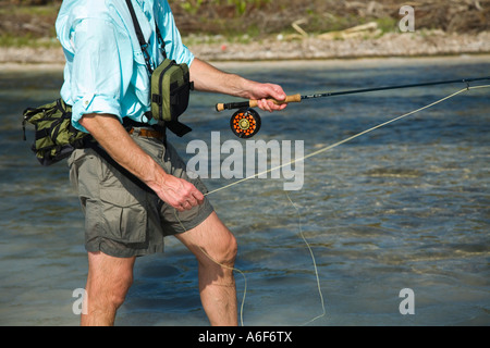 BELIZE Ambergris Caye erwachsenen männlichen Fliegenfischen in Wohnungen entlang der Küstenlinie auf Bonefish waten im seichten Wasser abstreifen Linie Stockfoto