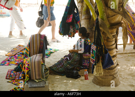 BELIZE San Pedro auf Ambergris Caye guatemaltekischen Frau sitzen im Palm Tree Schatten mit handgewebten Stoffen zum Verkauf Stockfoto