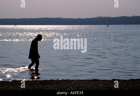 Ein einsamer alter Mann genießt einen Spaziergang in das Seewasser Seite in Bayern Stockfoto