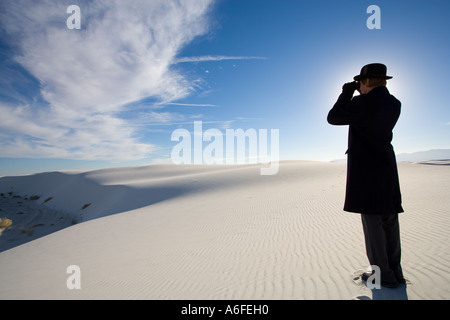 Mann trägt Mantel Blick durch ein Fernglas in Sanddüne Wüste Stockfoto