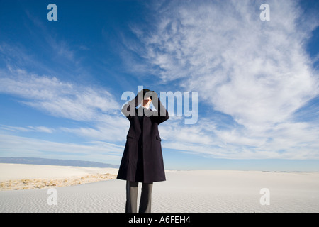Mann trägt Mantel Blick durch ein Fernglas in Sanddüne Wüste Stockfoto