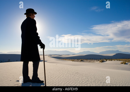 Mann mit Mantel und Bowler Hut mit Blick auf weiße Sanddüne Wüste Stockfoto