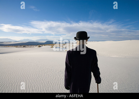 Mann mit Mantel und Bowler Hut mit Blick auf weiße Sanddüne Wüste Stockfoto