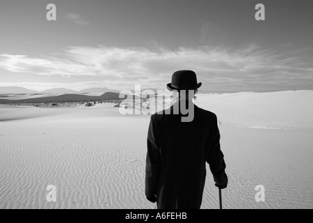 Mann mit Mantel und Bowler Hut mit Blick auf weiße Sanddüne Wüste Stockfoto