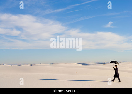 Mann mit Regenschirm im weißen Sand Düne Wüste wandern Stockfoto