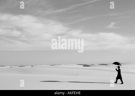 Mann mit Regenschirm im weißen Sand Düne Wüste wandern Stockfoto
