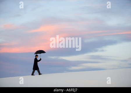 Mann mit Regenschirm auffällig eine humorvolle Pose in der Weißen Düne-Wüste Stockfoto