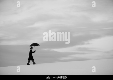 Mann mit Regenschirm auffällig eine humorvolle Pose in der Weißen Düne-Wüste Stockfoto
