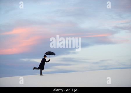 Mann mit Regenschirm auffällig eine humorvolle Pose in der Weißen Düne-Wüste Stockfoto