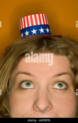 Junge Frau mit roten Haaren, die einen sehr kleinen Sternenbanner Hut Stockfoto