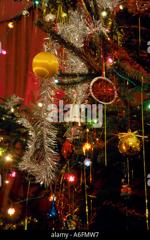 Weihnachtsbaum mit Dekorationen Baubels Glocken Lichtern Papier Ketten und Lametta Stockfoto