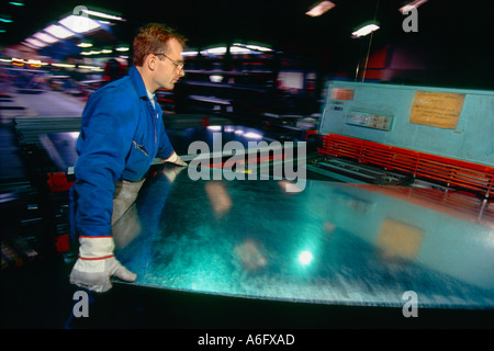 Ein Arbeiter in einer Fabrik laden Blech in einer hydraulischen Presse. Stockfoto