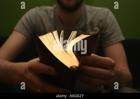 Blonder Jüngling Lesen der Bibel mit hellen grünen Hintergrund Stockfoto