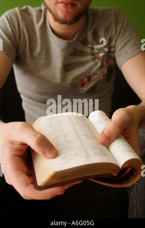 Blonder Jüngling Lesen der Bibel mit hellen grünen Hintergrund Stockfoto